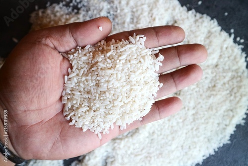 Photography A mound of rice resting on the palm of a hand, one of the most crucial staple food commodities in Asia, particularly Southeast Asia