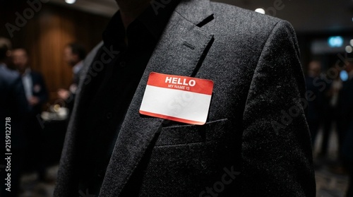 Blank name tag sticker on a businessman suit jacket during a corporate networking event at a conference hall with professional colleagues