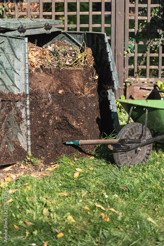 Compost bin with wheelbarrow in backyard garden