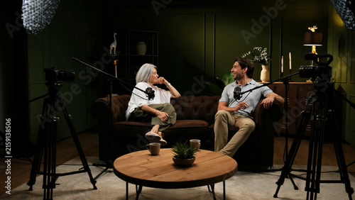 Two people engaging in a lively discussion with microphones and cameras during a live broadcast