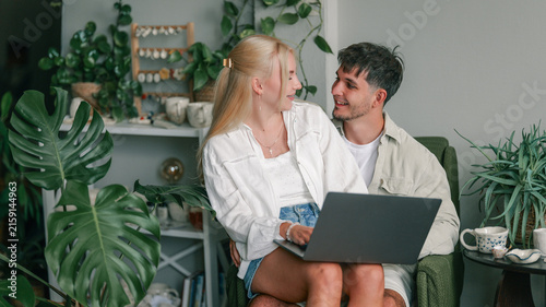 Photography Young couple happily interacting while using a laptop together at home