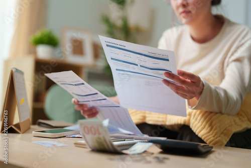 Woman checking payment due notices and household bills with cash and calculator at home, concept for overdue payments, monthly expenses, budgeting, financial stress and money management