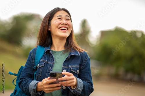 Happy East Asian woman using smart phone outdoors in nature