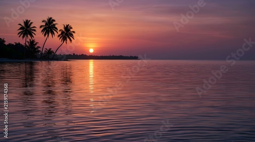 Tropical sunset over calm ocean with silhouette palm trees at dusk