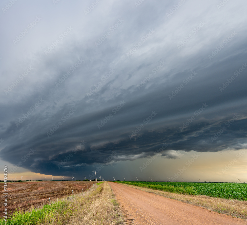 Obraz premium Remote dirt road framed by a storm in the Great Plains