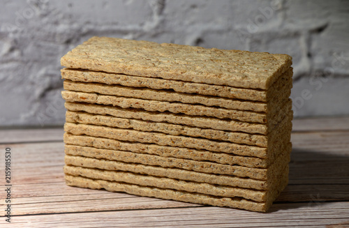 Foto Stack of rectangular crispbread on a wooden surface against a white brick wall