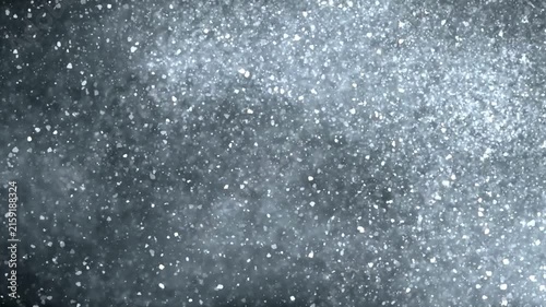 Dynamic snow flurry falling gently against dark textured background, winter blizzard motion footage, cold weather abstract atmospheric effect, cinematic slow motion.