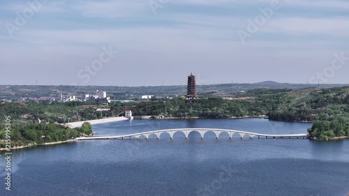 Scenic lake view with arched bridge and distant pagoda surrounded by hills and forests