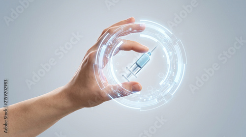 Human hand interacting with a digital hologram of a syringe to represent advanced medical research innovation and modern healthcare technology