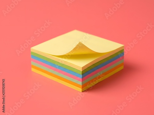 Vibrant stack of multicolored adhesive notes with a gently peeled corner on a warm pink background