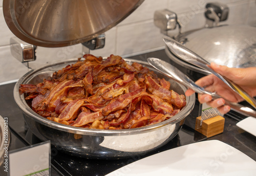 getting bacon from stainless steel container in breakfast buffet