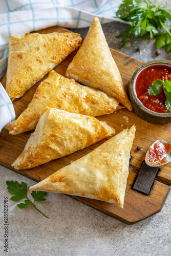 Traditional asian food. Vegetarian samsa (samosa) stuffed with potato with tomato sauce on a stone surface. Healthy breakfast,  snack. Copy space.