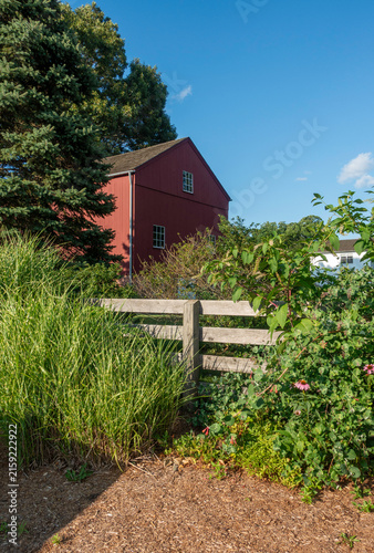 A red barn tucked behind a rustic wooden fence in Glastonbury, Connecticut (CT)