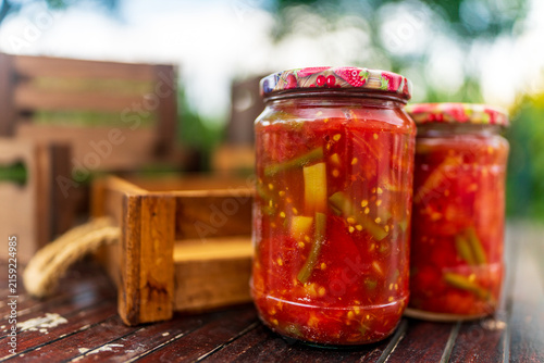 Glass jars filled with homemade pickled tomatoes and veggie mix for soup prepared for winter food preservation and storage
