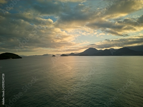 Golden sunset over tropical beach with silhouetted mountains and ocean, Brazil