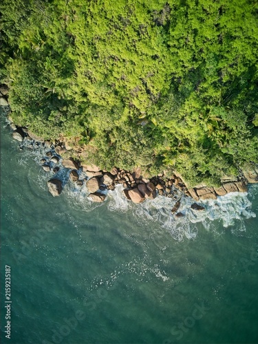 Top down aerial view of rocky coastline with Atlantic Forest and waves at dusk in Brazil