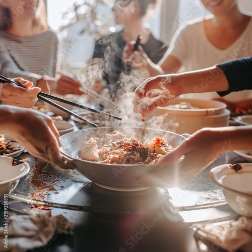 Steaming hot dish passed between hands on a rotating table during a cozy family reunion dinner, for China National Day and autumn holidays
