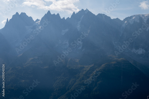 Dramatic summer view of rugged mountain peaks and forested slopes in the French Alps near Chamonix.