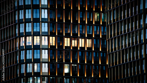 Foto Modern glass office building facade illuminated at night
