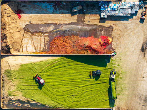 Aerial view of agricultural machinery processing green fodder at a food factory, with large piles of organic material and storage containers in Pomposa, Emilia-Romagna, Italy.