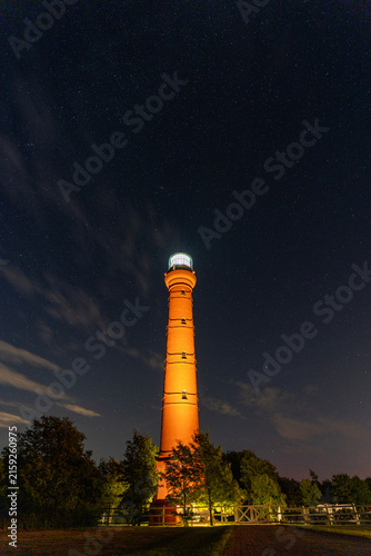 Pakri lighthouse glowing illuminated under starry night sky in Estonia