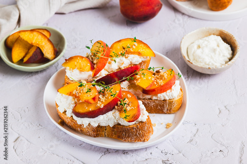 Fotografía Bruschetta with ricotta, peaches, and nuts on a plate on the table