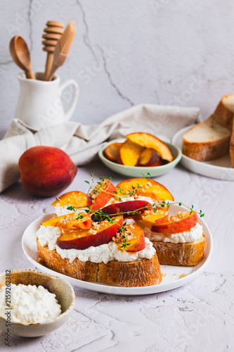 Fotografie Peaches, ricotta and thyme on ciabatta on a plate on a table vertical view