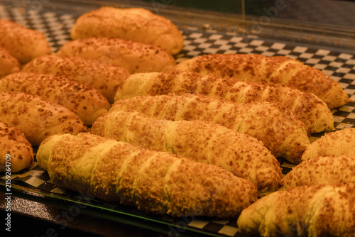 Photography Freshly baked golden cheese bread rolls arranged on display tray inside bakery s