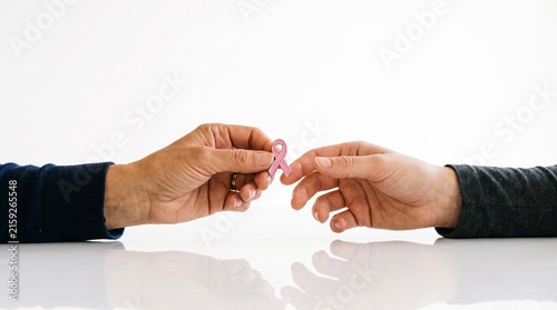 Hands exchanging pink ribbon symbol of breast cancer awareness and support