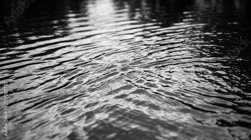A blurred, desaturated, transparent yet clear calm water surface texture featuring splashes and bubbles, set against a trendy abstract nature background with white‑grey waves illuminated by sunlight