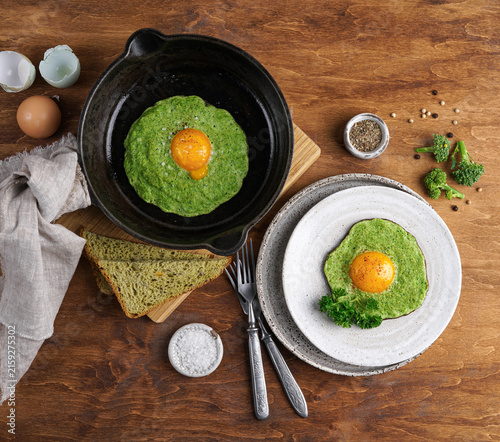 Healthy breakfast with fried eggs in broccoli nests on wooden background. Flat lay top view.