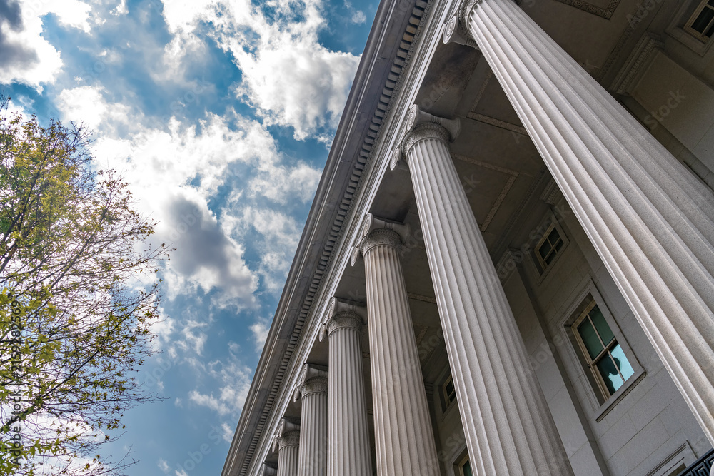 Fototapeta premium Low angle Treasury colonnade creates strong perspective against a bright cloudy sky.