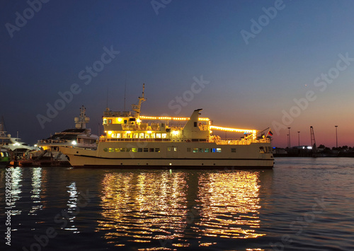 фотографія A large excursion ship, ablaze with lights, docked at the seaport at night