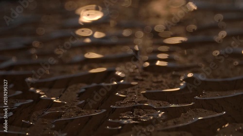 Sunset sunlight shines on transparent raindrops on a wooden surface, blurry background