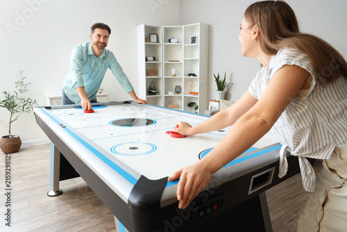 Young woman with her boyfriend playing air hockey at home