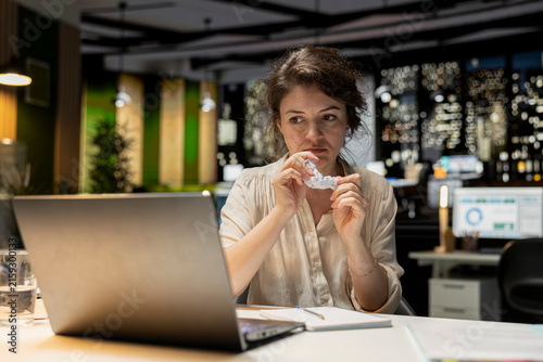Canvas Print Livid businesswoman breaks a paper page after making a mistake while handwriting notes in the office after hours, then redoes the draft on a new sheet while dealing with frustration at work