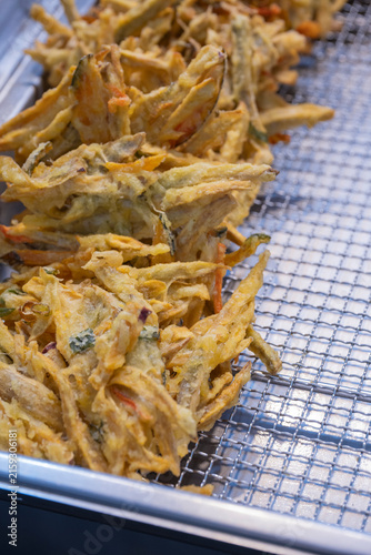 Foto Crispy golden deep fried mixed vegetable fritters neatly arranged on a wire rack at a local market in Korea