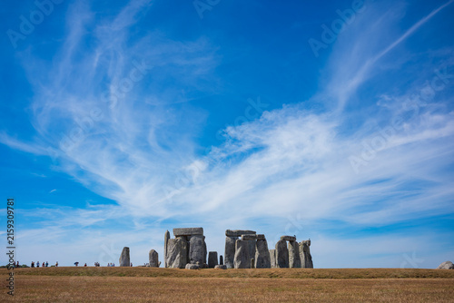The prehistoric megalithic structure Stonehenge during a summer afternoon with dry, brown grass in the foreground