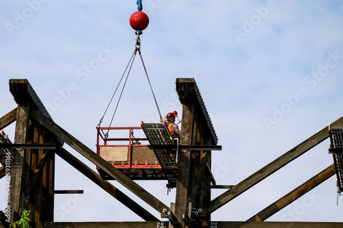 Obraz na płótnie Workman in safety equipment in work basket help aloft by crane, old wood railway