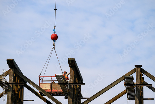 Картината върху платно Workman in safety equipment in work basket help aloft by crane, old wood railway