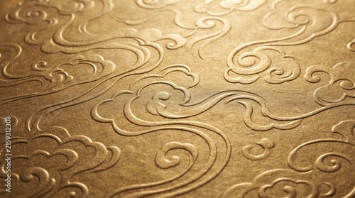 An intricate embossed pattern of swirling clouds in a golden hue, suggesting traditional artistry or luxury
