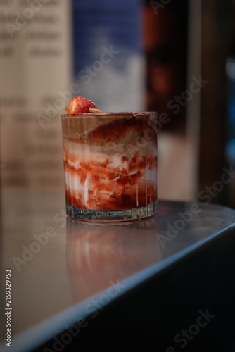 Layered strawberry chocolate dessert in a glass on a modern cafe counter
