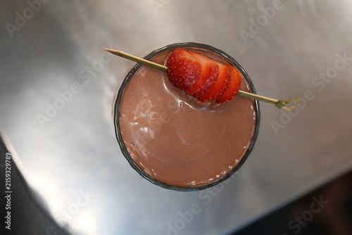 Chocolate smoothie in a glass with a fresh strawberry garnish, top down view.