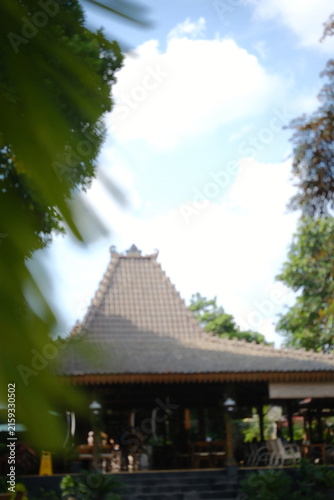 Traditional Javanese Joglo house architecture with wooden roof structure in tropical garden
