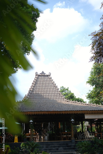 Traditional Javanese Joglo house architecture with ornate wooden roof structure.