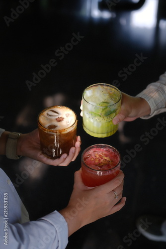 Person pouring vibrant green smoothie into glass from blender with fresh fruits on dark table