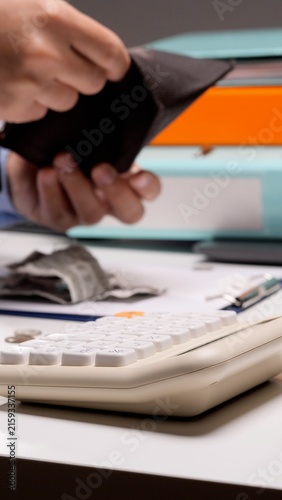 Cuadro en lienzo Person's hands opening an empty wallet above a desk with a calculator, documents