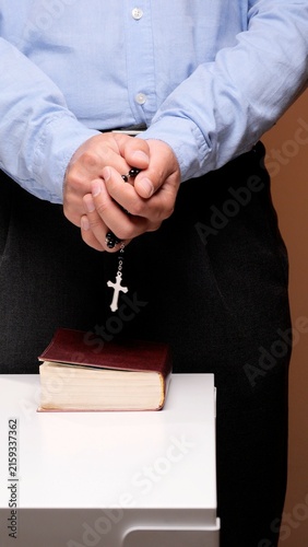Foto Person's hands clasped in prayer, holding a rosary with a crucifix while standin