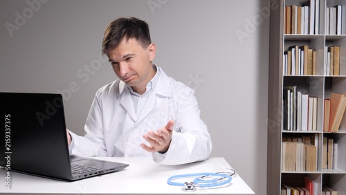 Foto Doctor in a white coat sitting at a desk, expressing frustration while looking a
