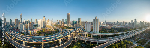 Photography A panoramic view of a modern urban area featuring a complex highway interchange and dense skyscrapers under a clear blue sky